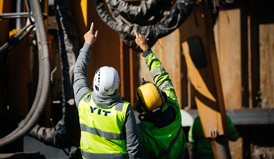 Två personer i arbetskläder pekar på en detalj i på arbetsplatsen